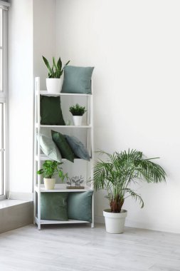 Yeşil yastıklı raf ünitesi ve aydınlatma odasında bitkiler.