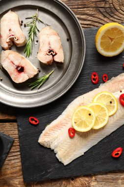 Limonlu çiğ morina fileto tahtası ve ahşap arka planda kesilmiş parçalar.