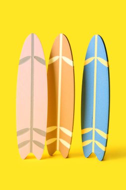 Sarı arka planda birçok farklı renkli mini sörf tahtaları