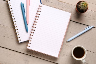 Kalemli defterler ve gri ahşap arka planda bir fincan lezzetli kahve.