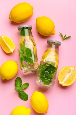 Pembe arka planda naneli lezzetli limonata şişeleri.