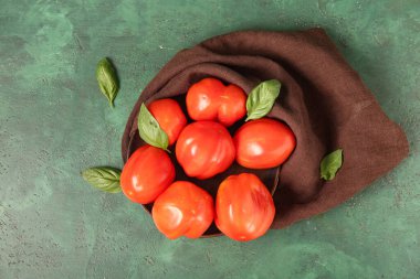 Taze olgun domatesli tabak ve yeşil arka planda fesleğen.