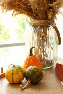 Ahşap mutfak tezgahında otlu balkabakları ve vazolar, yakın plan.