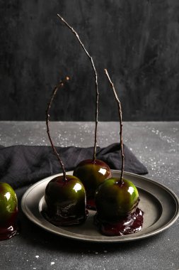 Siyah arka planda Cadılar Bayramı için lezzetli karamelli elma tabağı.