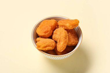 Sarı arka planda lezzetli nuggetlarla dolu bir kase