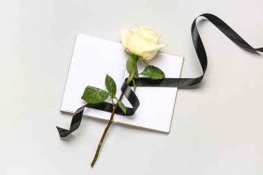 Siyah kurdeleli gül ve beyaz arkaplanda boş defter