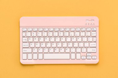 Turuncu arka planda pembe bilgisayar klavyesi. Üst görünüm