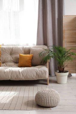 Oturma odasındaki pencerenin yanındaki rahat kanepe.