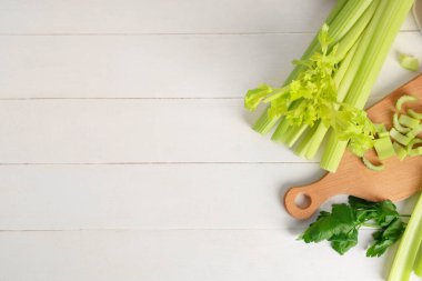 Beyaz ahşap masada taze yeşil kereviz tahtası.