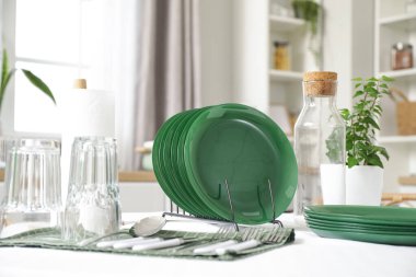 Mutfaktaki yemek masasında temiz tabaklar, çatal bıçak takımı ve bardaklar.