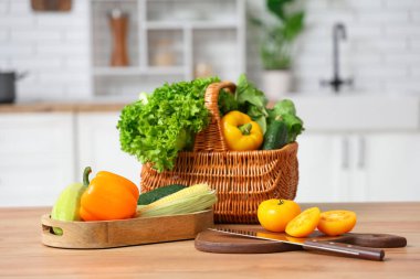 Tahta mutfak tezgahında farklı taze sebzelerle dolu sepet ve tahtalar.