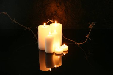Karanlık arka planda dikenli telle mum yakmak. Anma Günü
