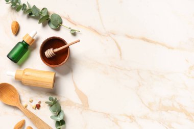 Ahşap kaşık, fındık ve okaliptüs şişeleri mermer arka planda gerekli yağ