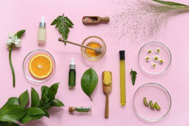 Petri kapları, doğal kozmetik ürünlerini pembe arka planda hazırlamak için numune ve malzemelerle dolu.