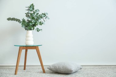 Okaliptüs dallarıyla dolu vazo beyaz duvarın yanındaki odada.