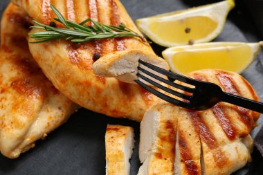 Izgara tavuk göğsü, biberiye, biber ve limon dilimleri, yakın plan.