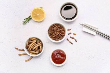 Farklı kızarmış böcekler ve beyaz arka planda soslar olan kaseler.