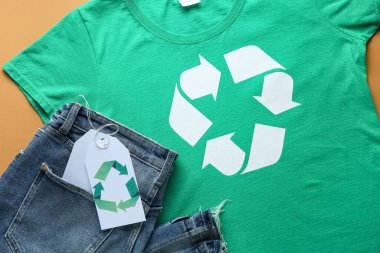 Turuncu arka planda geri dönüşüm logosu olan tişört ve kot pantolon