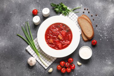 Bir kase lezzetli Ukrayna çorbası ve koyu arkaplanda malzemeler.