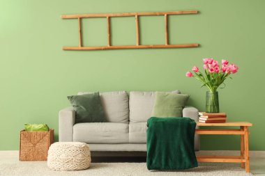 Gri kanepesi ve kahve masasında güzel lale çiçekleri olan şık bir oturma odası.