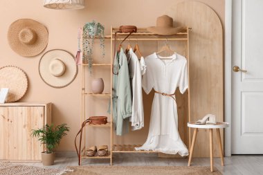 Koridorun iç tarafındaki bej duvarın yanında giysi ve aksesuarlarla dizilin.