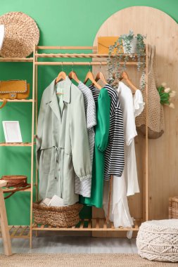 Koridorun iç tarafındaki yeşil duvarın yanında giysi ve aksesuarlarla dizilin.