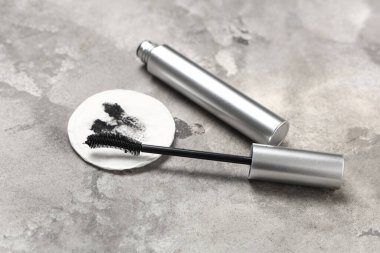 Kirli pamuk pedi ve gri grunge arka planında rimel olan kompozisyon, yakın plan.