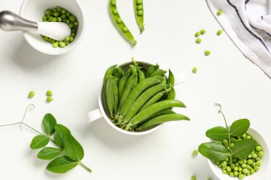 Taze yeşil bezelyeler ve beyaz arka planda kabuklar