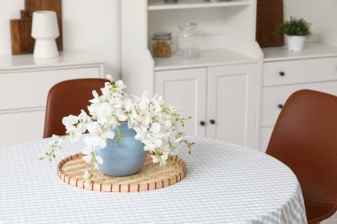 Mutfaktaki yemek masasında yapay çiçekli vazo.