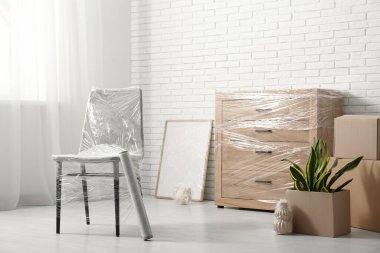 Taşındığı gün beyaz tuğla duvarın yanında streç film olan sarılı sandalye ve tuvalet.