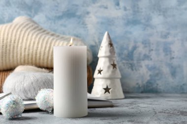 Noel toplarıyla yanan mum, kitap ve örgü ipliği grunge masasında, yakın plan