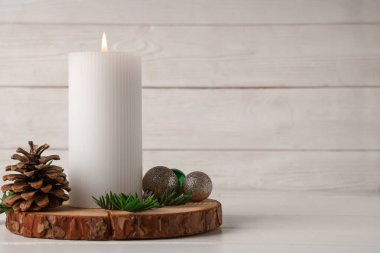 Beyaz ahşap masada yanan mum ve Noel süsü.