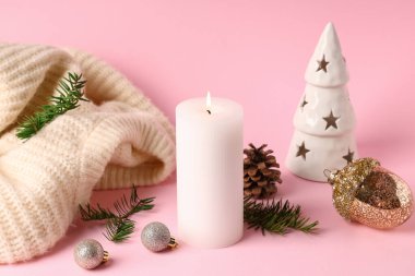 Noel dekorlu yanan mum ve pembe arka planda kazak.