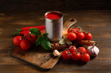 Teneke kutu lezzetli domates ezmesi ve ahşap arka planda farklı malzemeler, yakın plan.