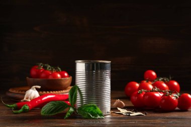 Teneke kutu lezzetli domates ezmesi ve ahşap arka planda farklı malzemeler.