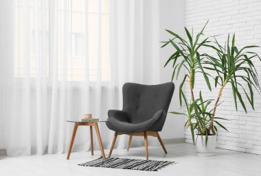 Koltuk, kahve masası ve ev bitkisi oturma odasının içinde.