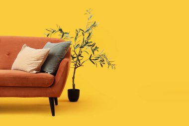 Yastıklı kanepe ve sarı arka planda bitkiler