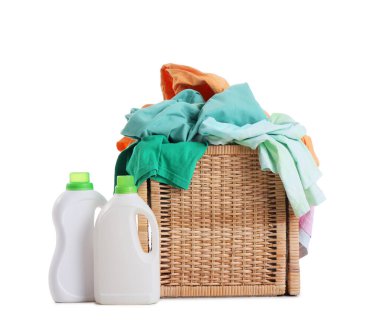 Kirli giysileri ve beyaz arka planda izole edilmiş deterjan şişeleriyle dolu hasır çamaşır sepeti.