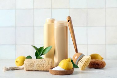 Beyaz kiremit duvarının yanındaki masada limon ve bitki yapraklı doğal temizlik malzemeleri var.