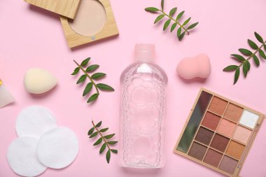 Pembe arka planda Micellar su, pamuk pedleri ve kozmetik ürünler
