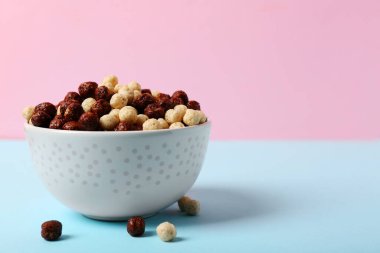 Renkli arkaplanda lezzetli çikolatalı mısır topları olan kase