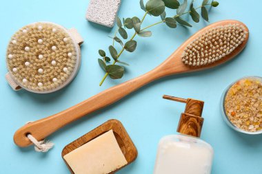 Masaj vücut fırçaları, sabun çubuğu ve mavi arka planda bir şişe kozmetik ürünü içeren kompozisyon, yakın plan.