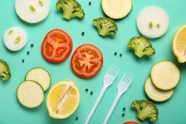 Turkuaz arka planda taze sebze ve plastik çatallı kompozisyon, yakın plan.