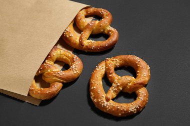 Siyah arka planda lezzetli krakerlerin olduğu kağıt torba, yakın plan.