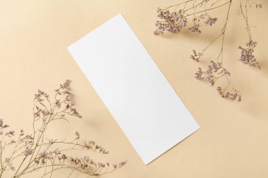 Boş kartla kompozisyon ve bej arkaplanda kurumuş çiçekler, yakın plan.