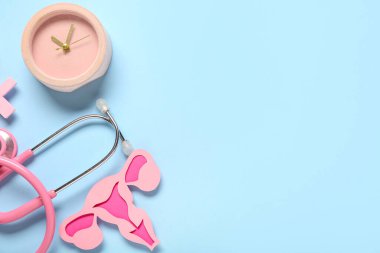 Steteskoplu saat ve mavi arka planda kağıt rahim. Jinekoloji konsepti