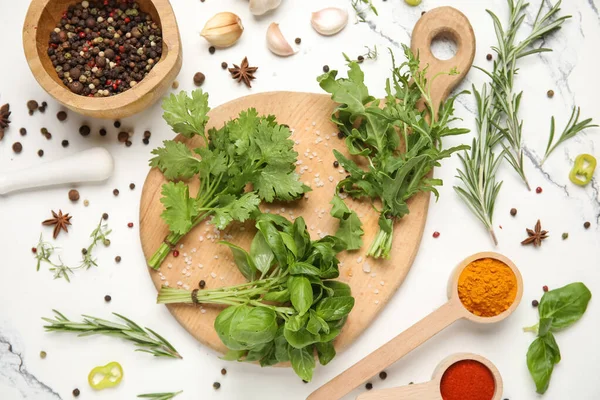 Ahşap kesim tahtası, mermer arka planda bitkiler ve baharatlar, yakın plan.