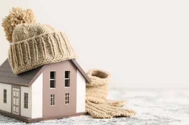 Kış kompozisyonu dekoratif ev, sıcak eşarp ve beyaz arka planda grunge masasında şapka