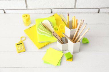 Farklı kırtasiye malzemesi ve ahşap masadaki not defterleriyle tutucu.