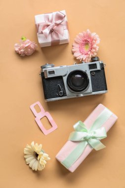 Renkli arkaplanda Uluslararası Kadınlar Günü için fotoğraf makinesi, çiçek ve hediyeli kompozisyon